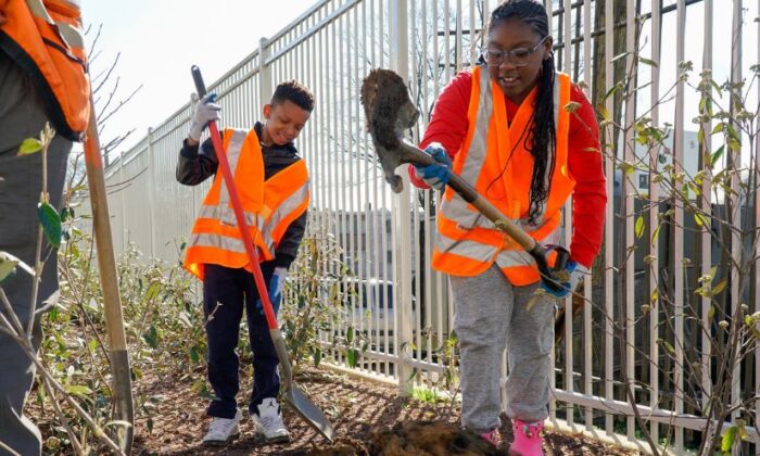 Two students dig a hole as they learn how trees are planted