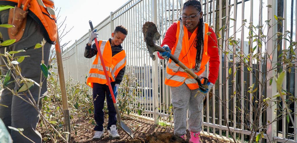 Two students dig a hole as they learn how trees are planted