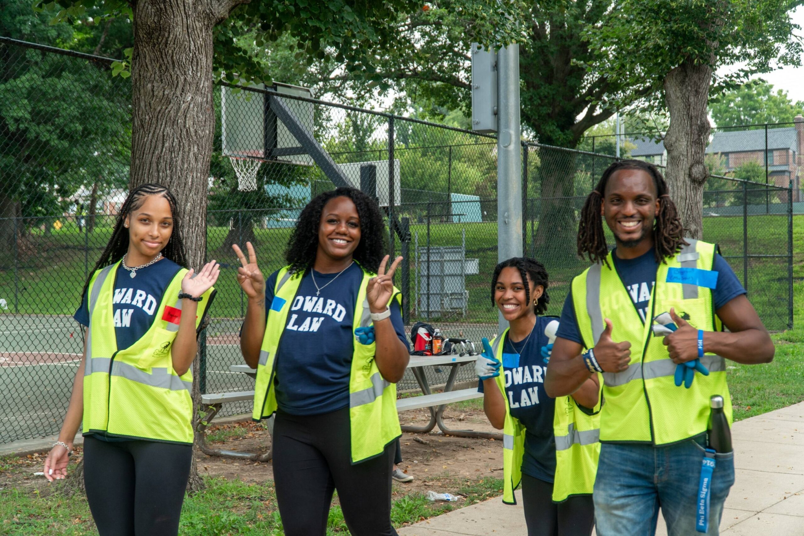 Four incoming Howard University Law students smile as they throw up peace signs and thumbs-ups for the camera.
