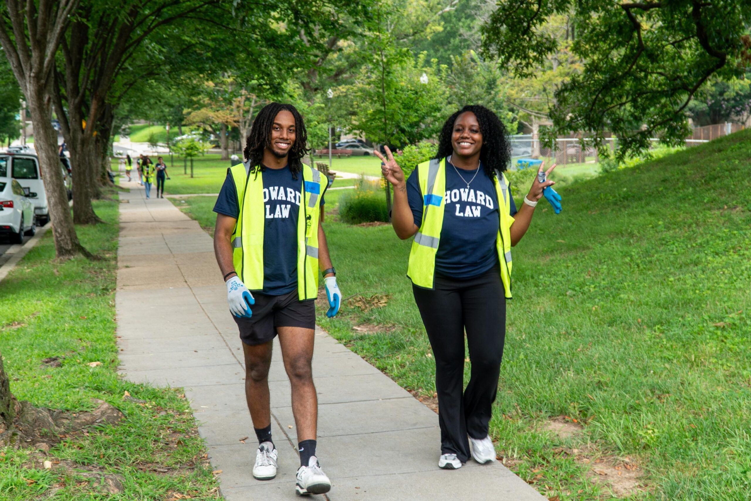 Two incoming Howard University Law students smile for the camera as they walk to lunch. One of the students throws up two peace signs.