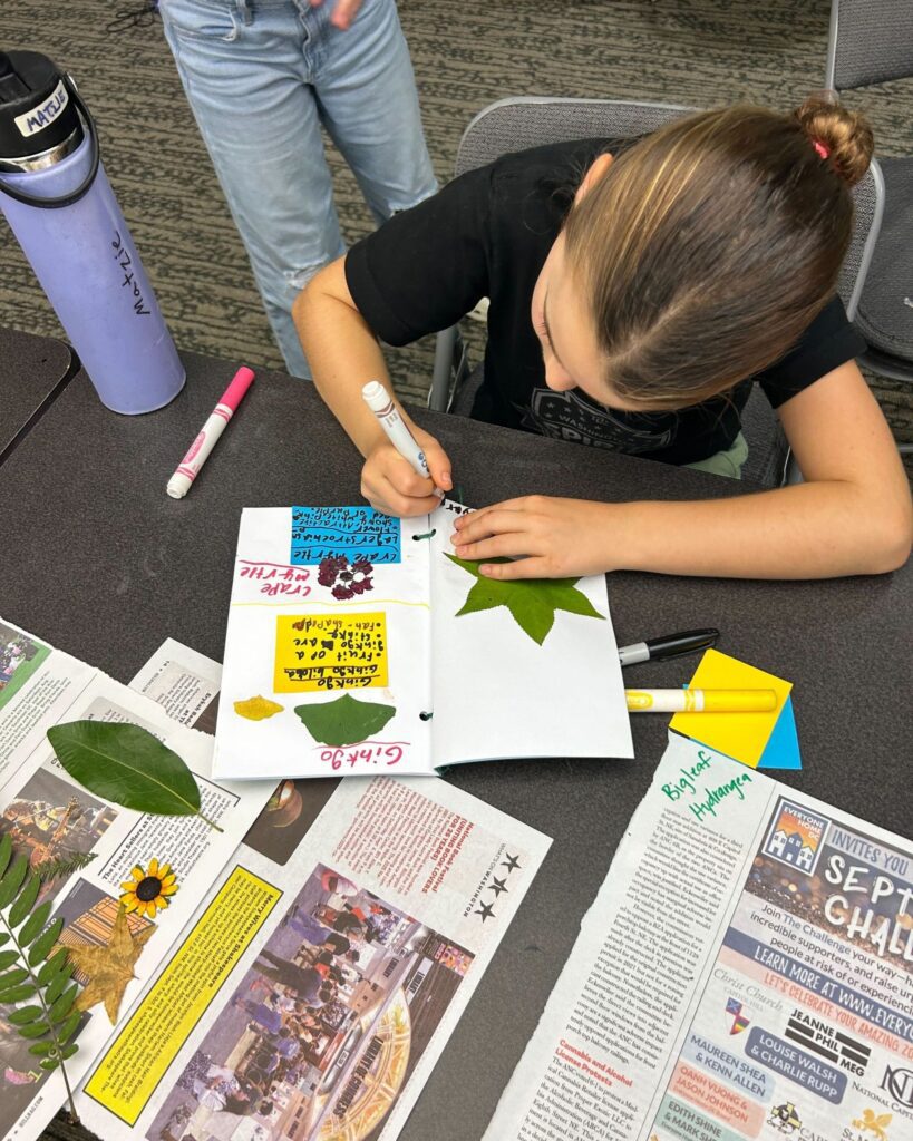 A young camper writes in their nature journal.