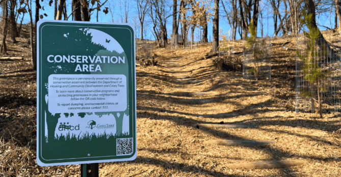 A large sign labels a forested area in the background as a Conservation Area