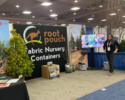 Exhibitioner for Root Pouch smiles in front of their booth.