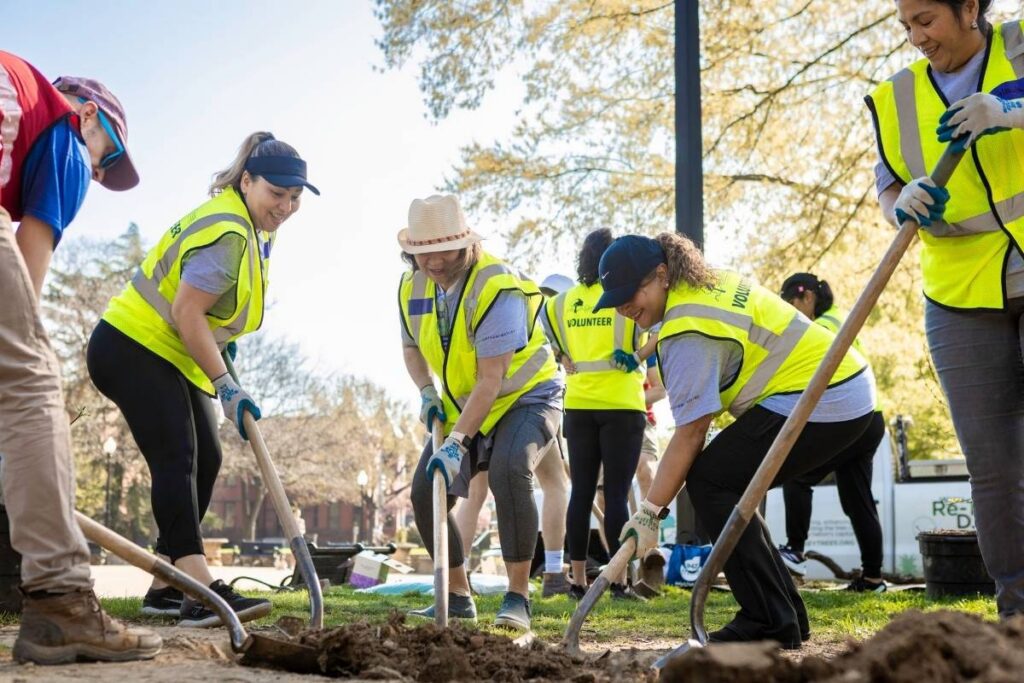 Volunteers smiling while planting a tree.