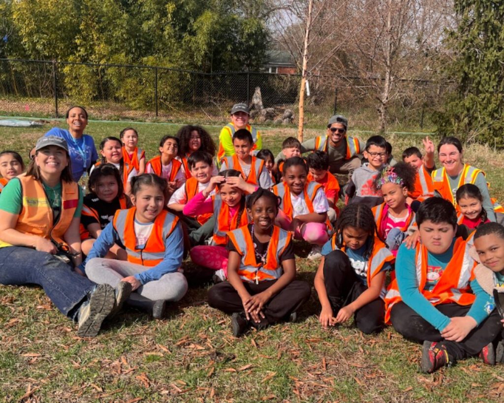 A group of students, teachers, and Casey Trees staff sit and smile.