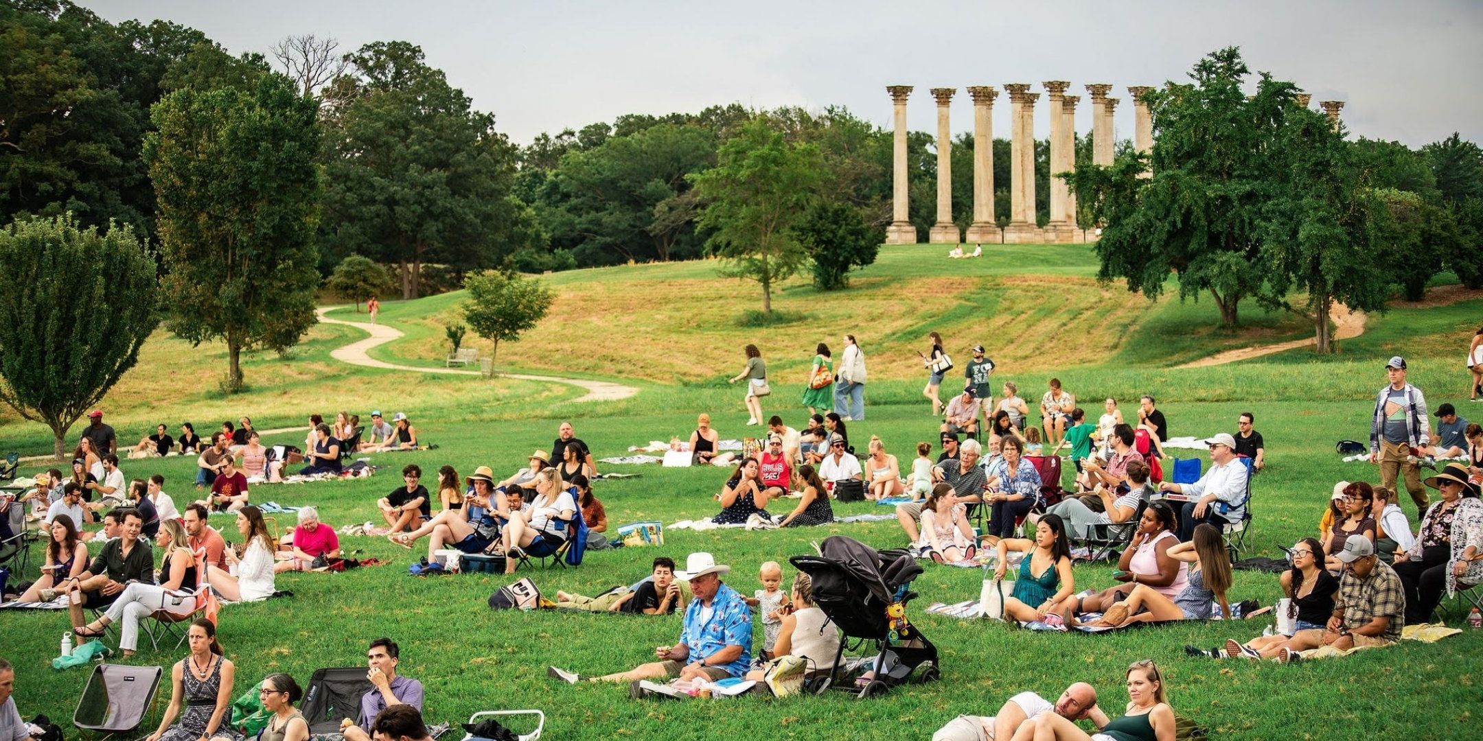 People sit in the meadow at the National Arboretum.