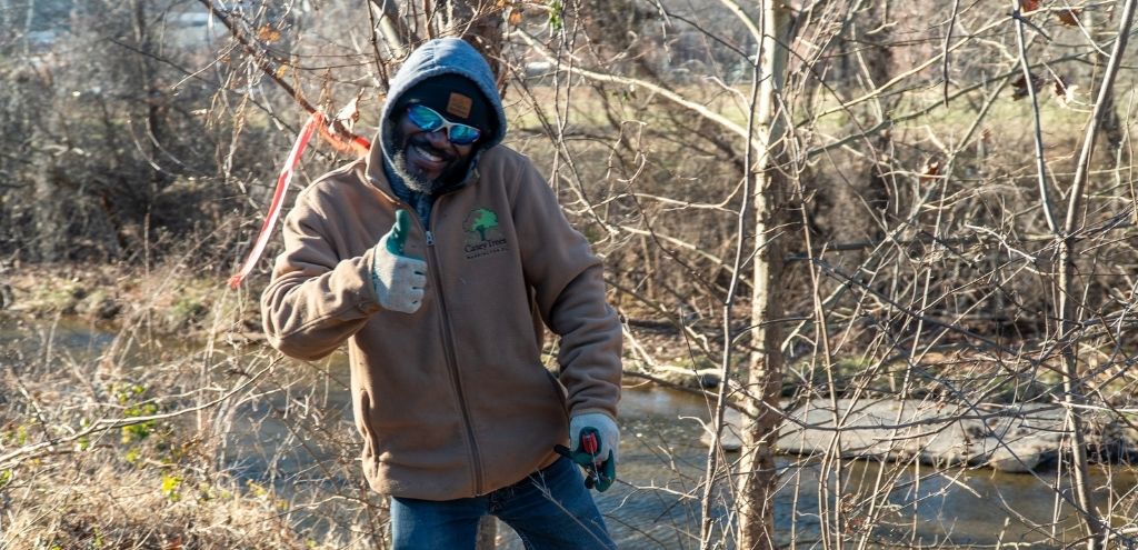 A Casey Trees staff member smiles and gives a thumbs up at the camera.