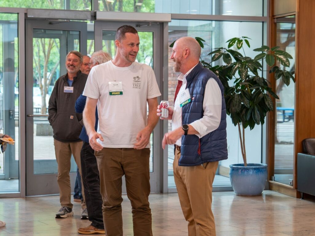 Speakers Tom Hill and Dr. Beau Brodbeck smile as they talk in the main hall of the Silver Spring Civic Center.